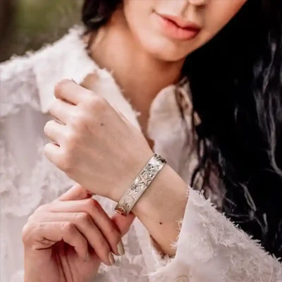 Woman wearing a silver western cuff bracelt with custom golden figure